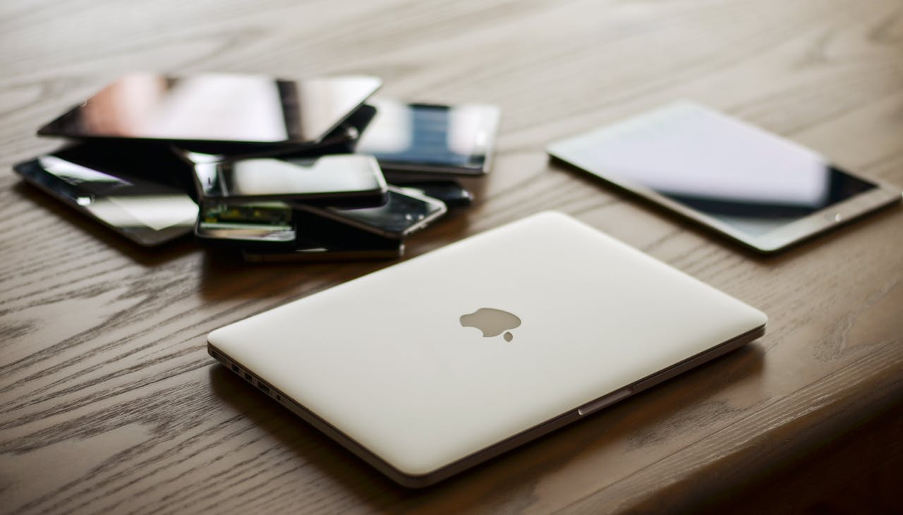 why-choose-us A variety of modern electronic gadgets, including a laptop and smartphones, on a wooden table.