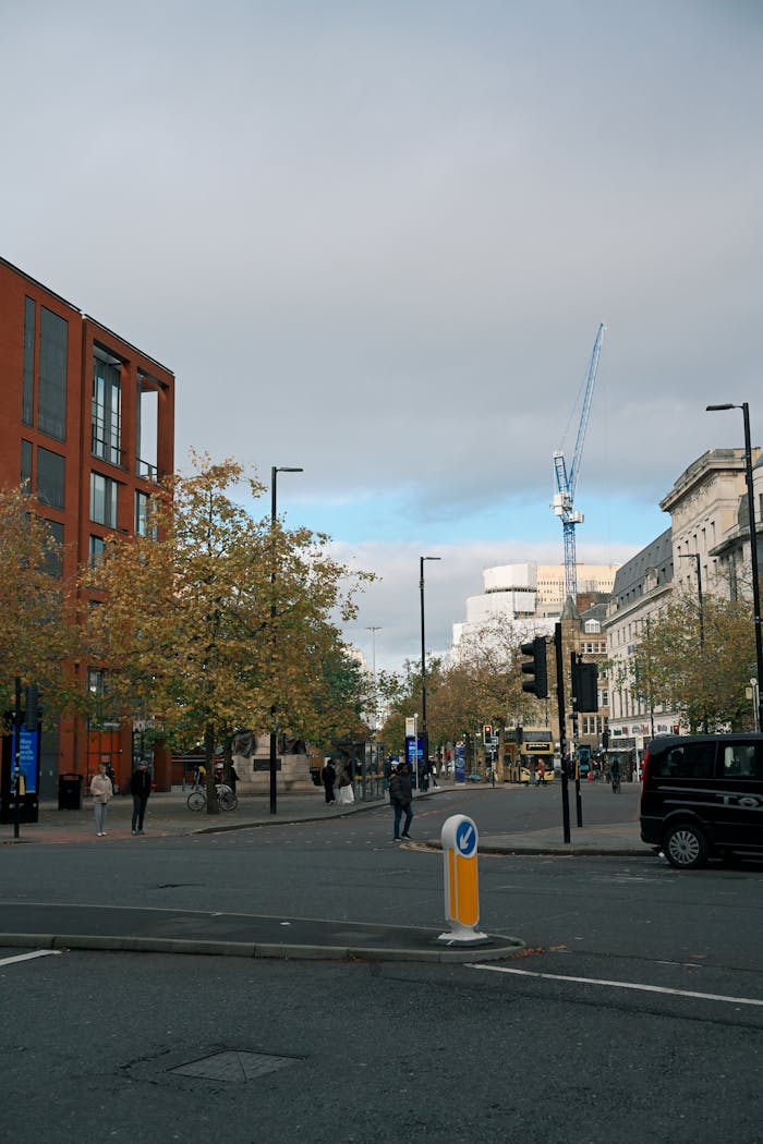 our-services-2 Urban street scene with a crane, people, and fall foliage in a bustling city.