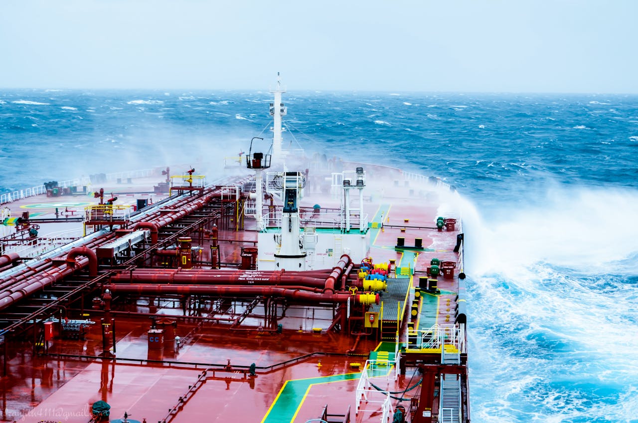 gallery-2 A cargo ship navigating through rough ocean waves on a bright day.