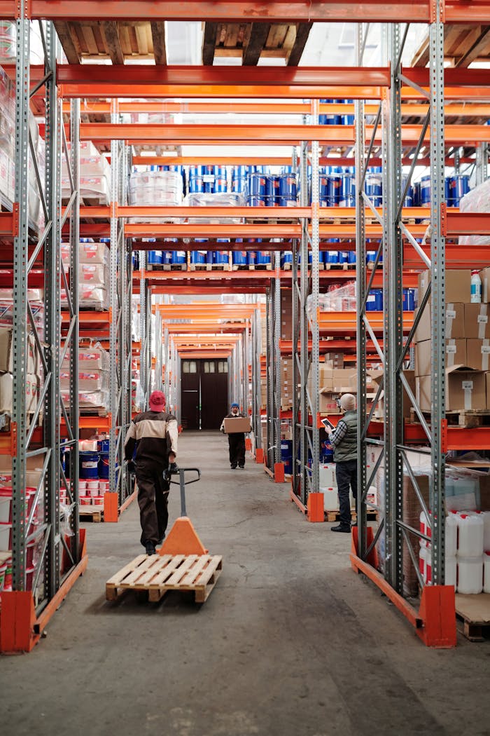 gallery-1 Workers arrange inventory on shelves in a large industrial warehouse.
