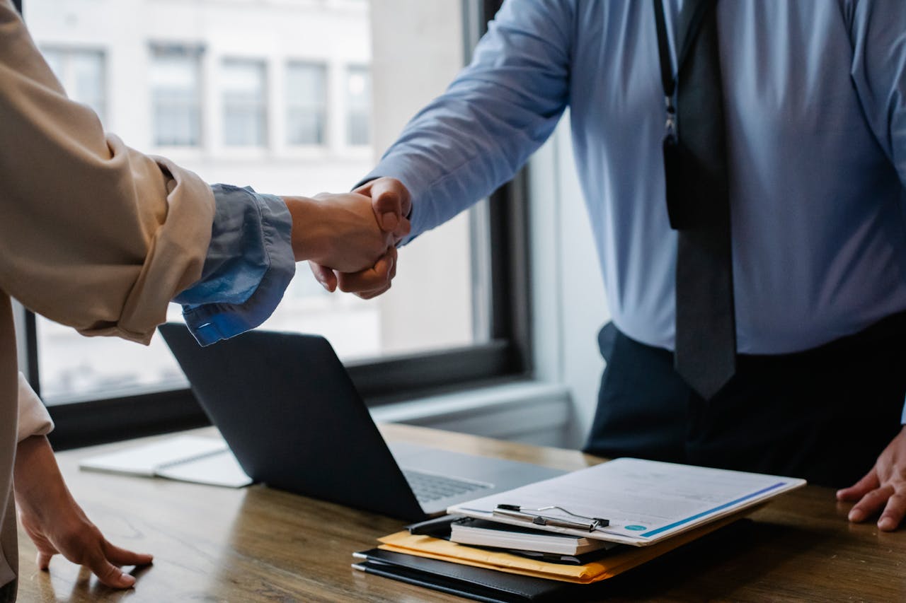 Mastering the First Impression: Your intriguing post title goes here Crop unrecognizable coworkers in formal wear standing at table with laptop and documents while greeting each other before meeting