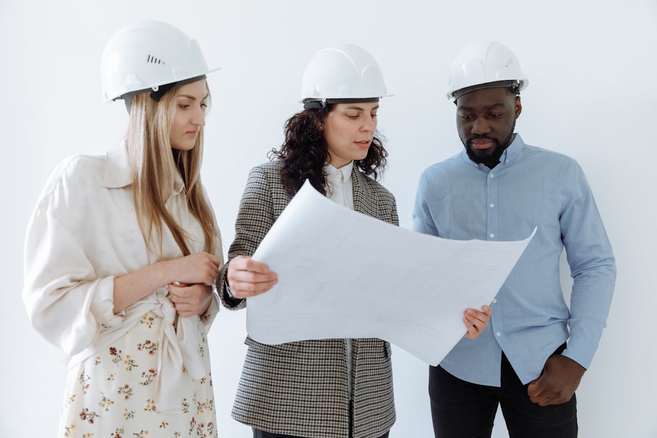 The Art of Drawing Readers In: Your attractive post title goes here Three architects wearing hard hats reviewing blueprints indoors for a construction project.